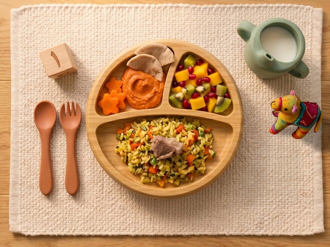 Bamboo divided toddler plate with rice, mixed veggies and pasta; wooden spoon and fork, milk cup, toy